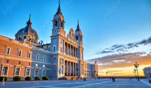 Madrid, Spain. Cathedral Santa Maria la Real de la Almudena at Plaza de la Armeria. Famous landmark with sunset sunand. Street lamps and picturesque sky with clouds. photo