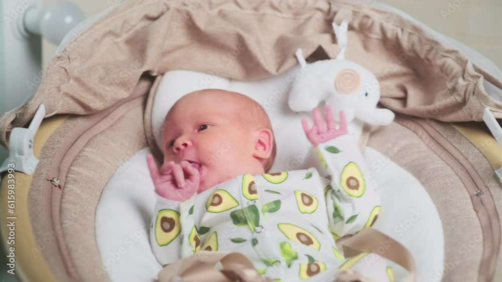 Newborn baby in electronic swing. A child on an electronic swing, automatic electrical chair. Electric pumps for newborns for infant motion sickness Newborn baby in electronic swing. A child on an electronic swing, automatic electrical chair. Electric pumps for newborns for infant motion sickness