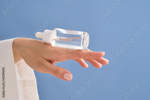 Serum with a pipette in female hands on a blue background.