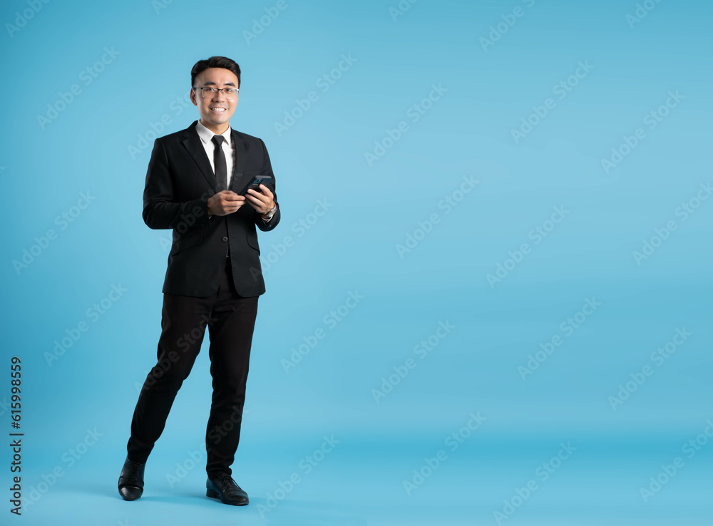 full body image of young businessman using phone on blue background full body image of young businessman using phone on blue background