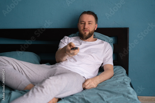 Watching tv in bedroom. Cozy weekend at home. Man watching movie in the morning.