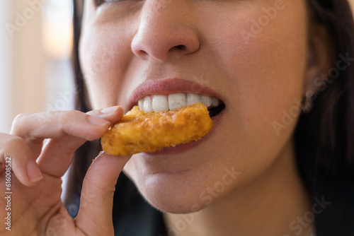 taking a bite of a piece of fried nugget  enjoying fast food  close up of the mouth  lips and teeth  lifestyle and tasting