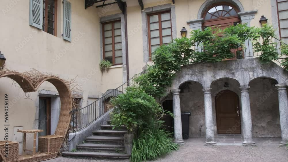 Romantic architecture in Annecy. Courtyard with foyer, double staircase and vine around it, with seat for two in heart made of straw. France. Romantic architecture in Annecy. Courtyard with foyer, double staircase and vine around it, with seat for two in heart made of straw. France.