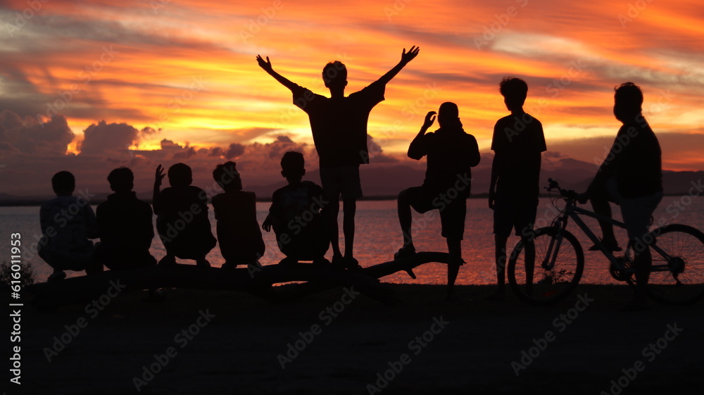 Silhouette of a group of young people on the lake at sunset Silhouette of a group of young people on the lake at sunset