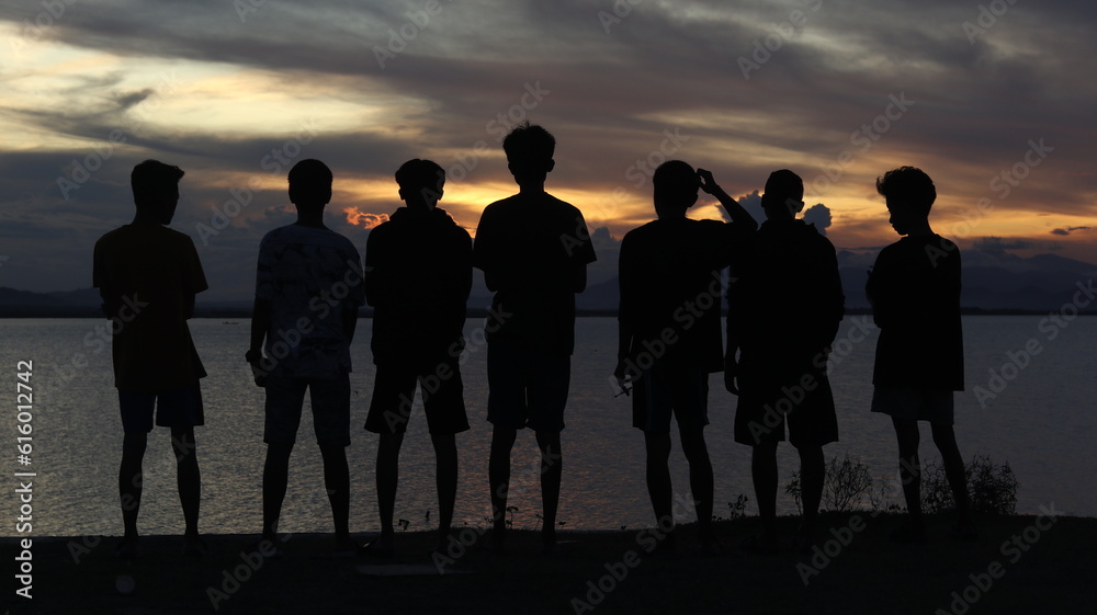 Silhouette of a group of people by the lake with a beautiful sunset