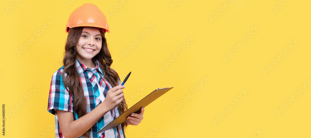 Engineer teenager girl. cheerful kid in construction helmet making notes in clipboard, taking notes. Child builder in helmet horizontal poster design. Banner header, copy space.