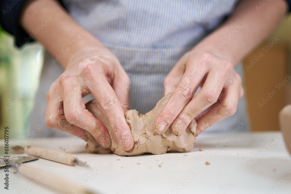 Closeup hands of ceramic artist wedging clay in art studio