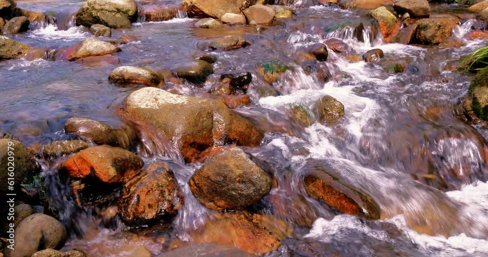 Close up on the flowing water background.The turbulent water flows through the rocky beach Close up on the flowing water background.The turbulent water flows through the rocky beach