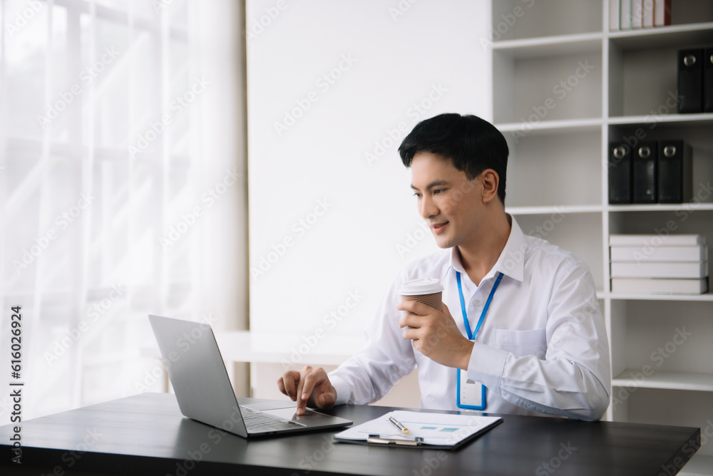Confident Asian man with a smile standing holding notepad and tablet at the modern office. Confident Asian man with a smile standing holding notepad and tablet at the modern office.