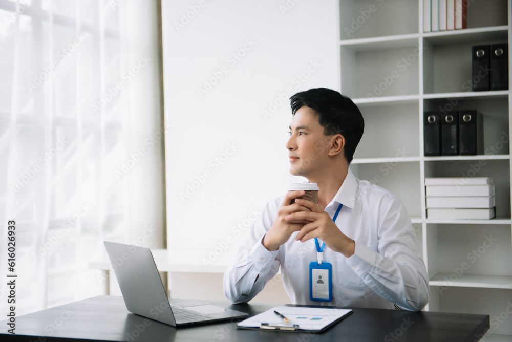Young Asian business man using laptop and tablet while sitting at her working place. Concentrated at work. Young Asian business man using laptop and tablet while sitting at her working place. Concentrated at work.