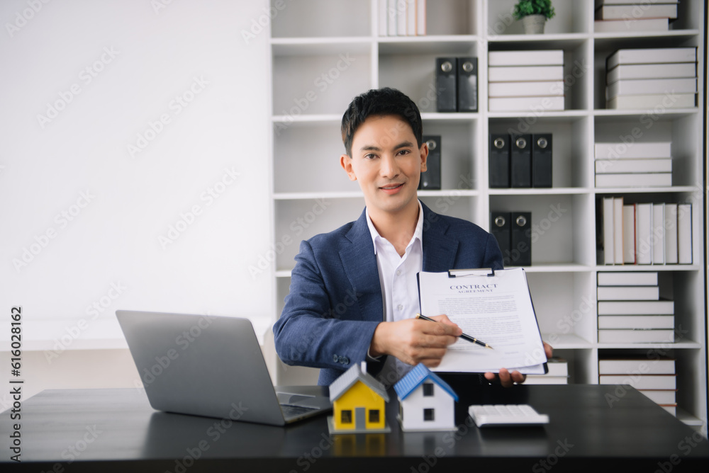 Asian man working with House model real estate agent and customer discussing for contract to buy house, insurance or loan real estate consult concerning mortgage loan offer Asian man working with House model real estate agent and customer discussing for contract to buy house, insurance or loan real estate consult concerning mortgage loan offer