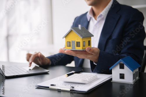 Real estate broker agent presenting to customer to decision making sign insurance form agreement, buy and sell home model, concerning mortgage loan offer