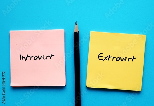 notepad on blue copy space background with handwritten text - INTROVERT EXTROVERT, different traits personalities - Introverts tend to feel drained after socializing while extroverts feel energized photo
