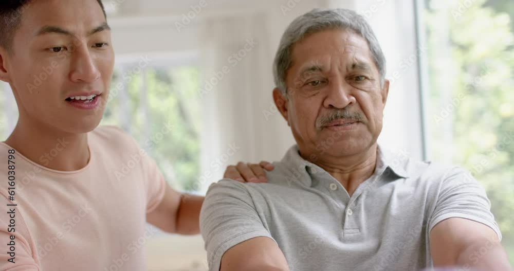 Diverse male physiotherapist advising and determined senior man using dumbbells, in slow motion Diverse male physiotherapist advising and determined senior man using dumbbells, in slow motion