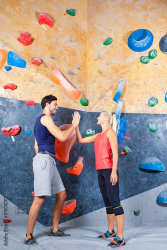 Sporty Couple of Caucasian Athletes Connecting Hands on High Five Together Before Steep Rock climbing Indoors As Extreme sports and bouldering concept.