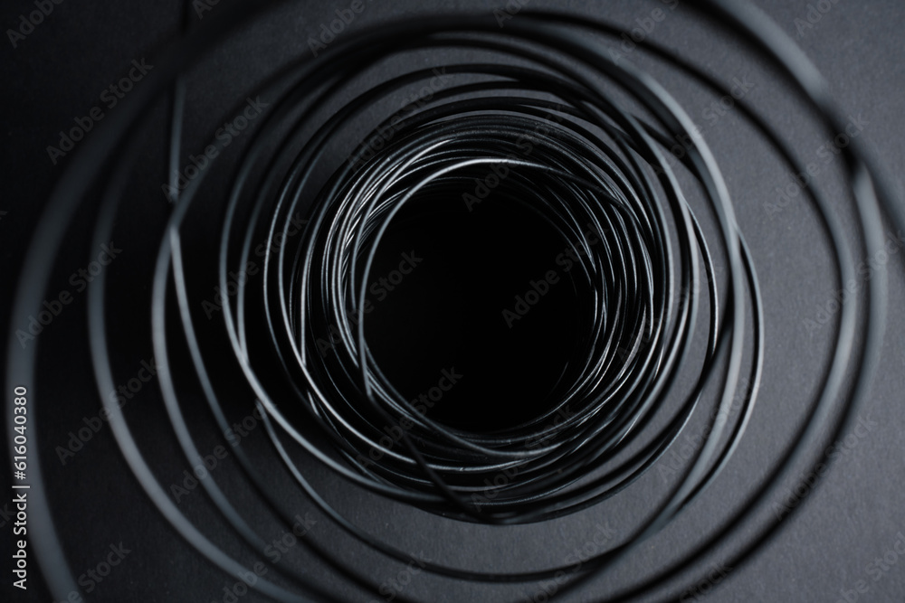 dark background on gray paper background black wire twisted into a spiral dark background on gray paper background black wire twisted into a spiral