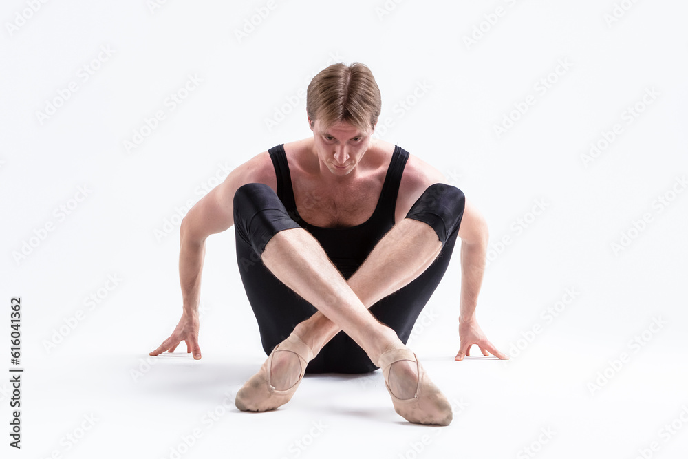 Closeup Image of Male Ballerino Dancer Sitting While Practising Stretching Exercices In Black Sportive Tights in Studio Closeup Image of Male Ballerino Dancer Sitting While Practising Stretching Exercices In Black Sportive Tights in Studio