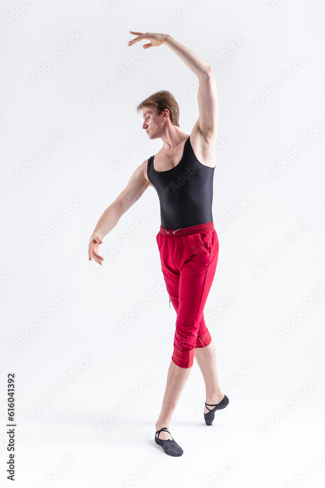 Stretching of Concentrated Contemporary Ballet Dancer Flexible Athletic Man Posing in Red Tights in Ballanced Dance Pose With Hands Lifted on White.