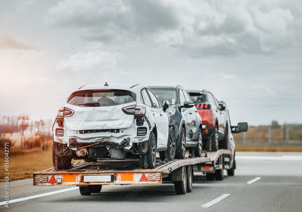 Emergency roadside assistance on the highway. side view of the fltabed tow truck with a damaged vehicles after a traffic accident.