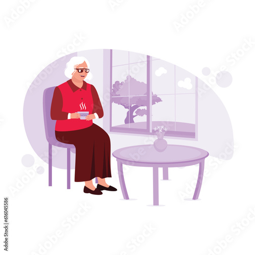 An older woman with glasses sits leisurely by the window, sipping hot tea. Trend Modern vector flat illustration.