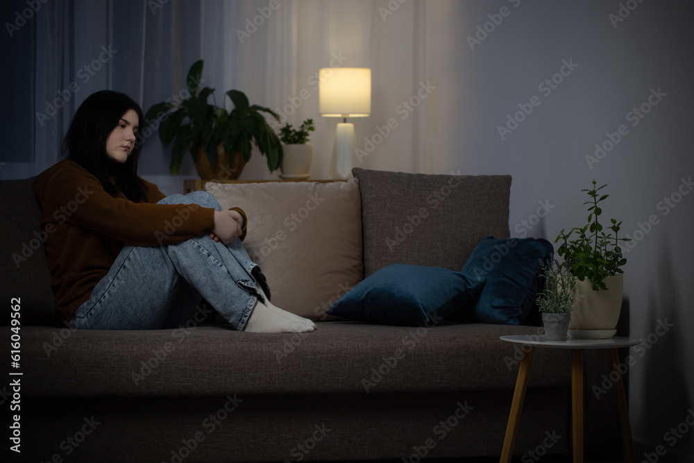sad teenager girl sitting on couch indoor at night sad teenager girl sitting on couch indoor at night