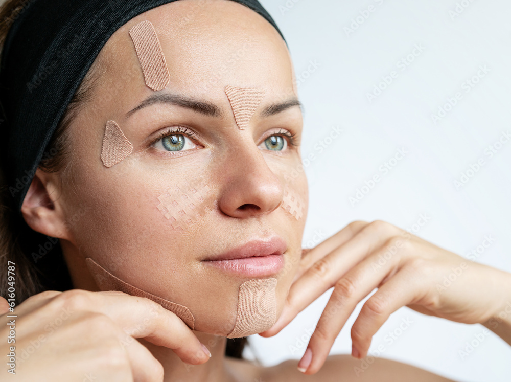 Female face with kinesio tapes for the face closeup. Beauty, lifting