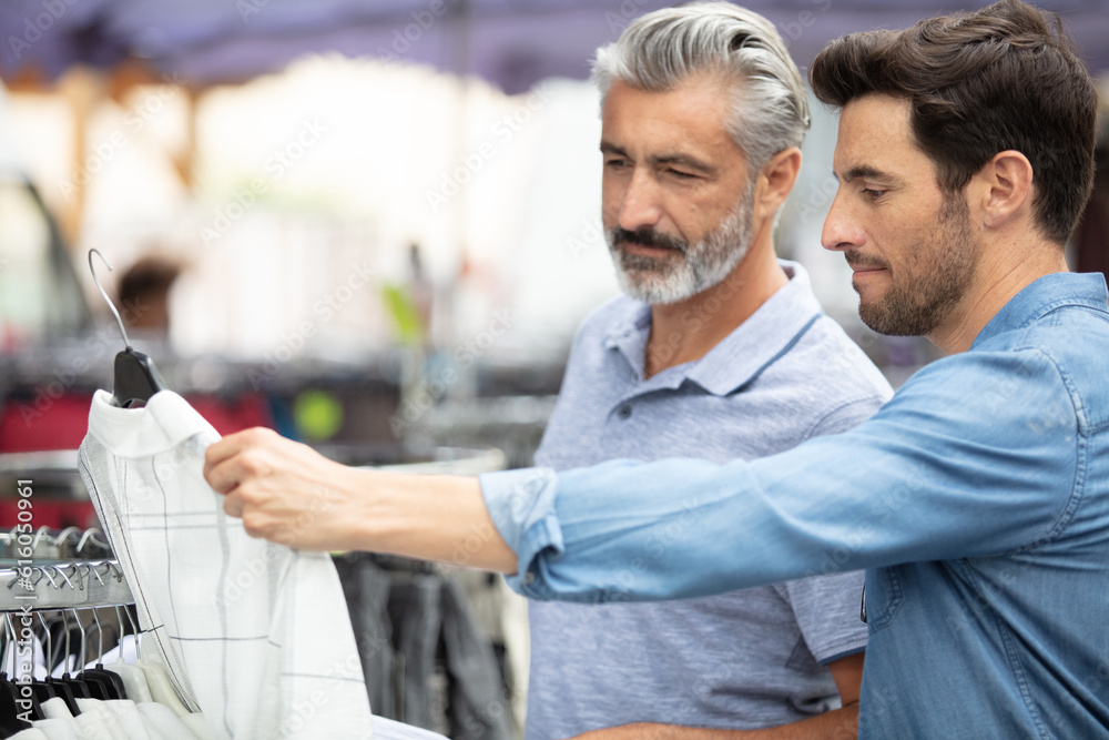 two men looking at a shirt on a street market two men looking at a shirt on a street market