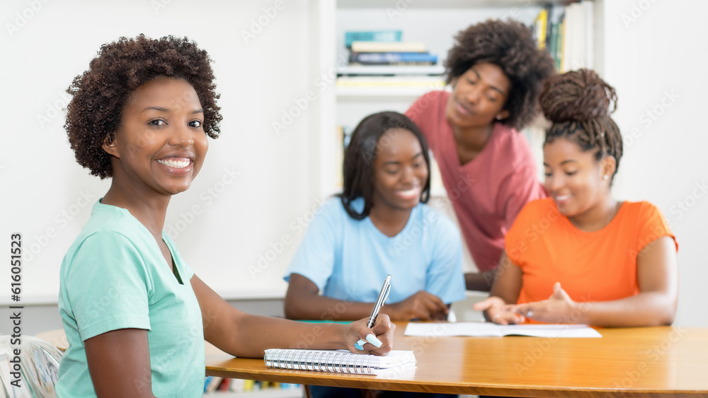 Laughing black female student at desk with group of learning african american students Laughing black female student at desk with group of learning african american students