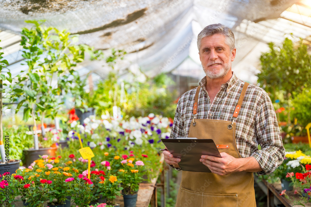 Gardener or florist man working in a nursery inside the greenhouse of plants and flowers Gardener or florist man working in a nursery inside the greenhouse of plants and flowers