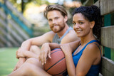 guy and girl in sportswear taking rest after playing basketball
