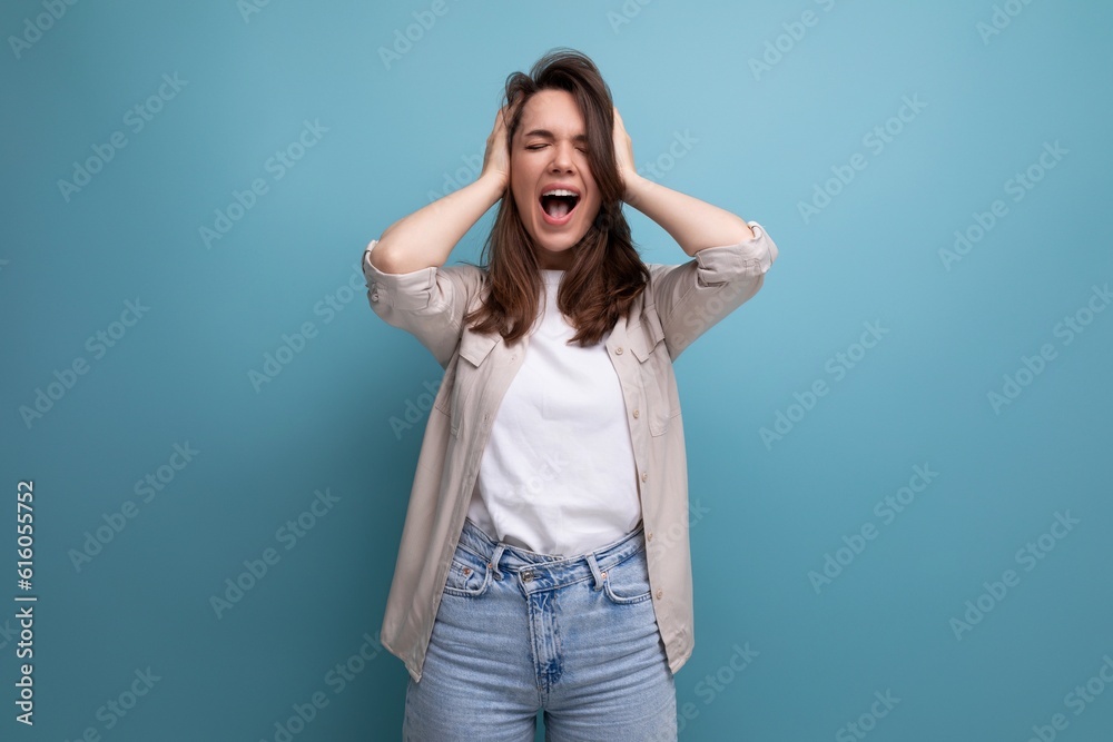 young dark-haired lady in informal clothes screaming on a blue background
