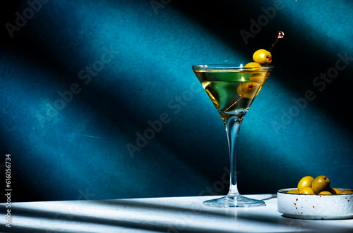 Vodka martini with olives, alcoholic cocktail drink with vodka and vermout, dark green background, bright hard light and shadow pattern, copy space photo