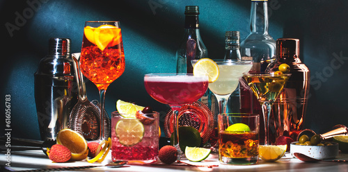 Slika na platnu Alcoholic cocktails set, strong drinks and aperitifs, bar tools, bottles on dark green background, hard light