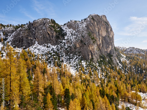 In an alpine setting, the majestic Dolomites are tinged with the warm autumn colors, while the imposing larches are colored with orange and gold, creating a breathtaking spectacle
