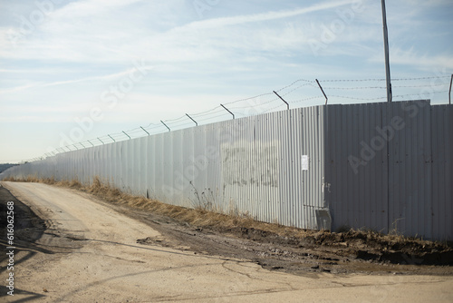 Fence in industrial zone. Road along territory. Passage between fences.