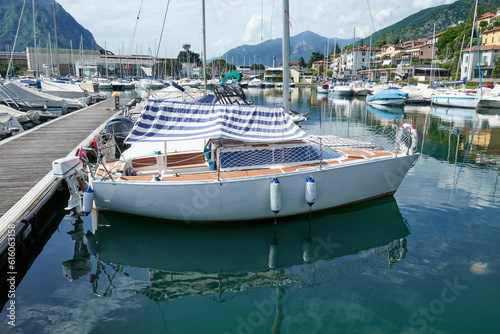 A beautiful white sailing ship is elegantly moored in the placid waters of a picturesque Italian lake port.