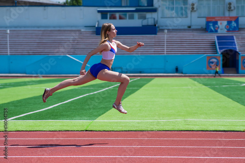 Young caucasian woman is engaged in jogging at the stadium outdoors.