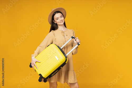 Young woman with a suitcase on a yellow background