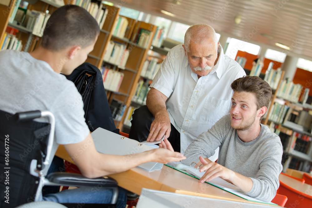 man with student in wheelchair in the library man with student in wheelchair in the library
