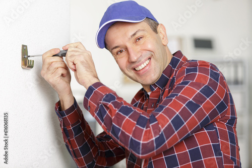 Fotografie a happy man screwing a hook to the wall