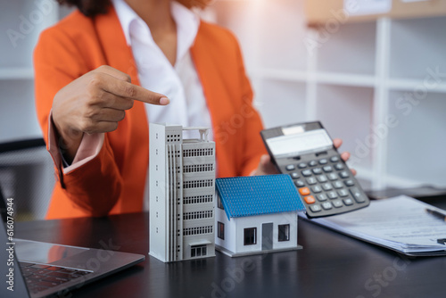 home loan officer uses a calculator with a house plan.