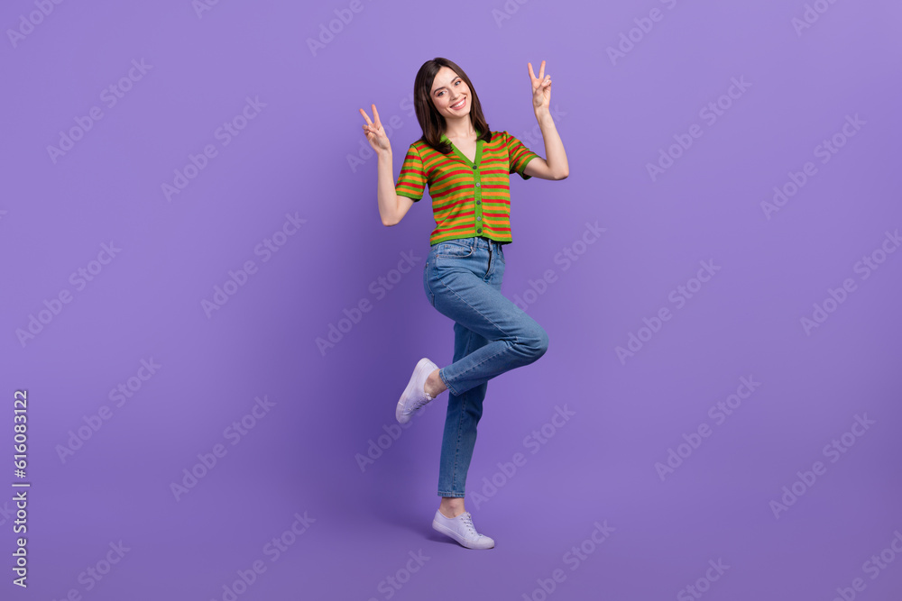 Full length photo of pretty adorable woman dressed striped cardigan showing two v-signs isolated violet color background Full length photo of pretty adorable woman dressed striped cardigan showing two v-signs isolated violet color background