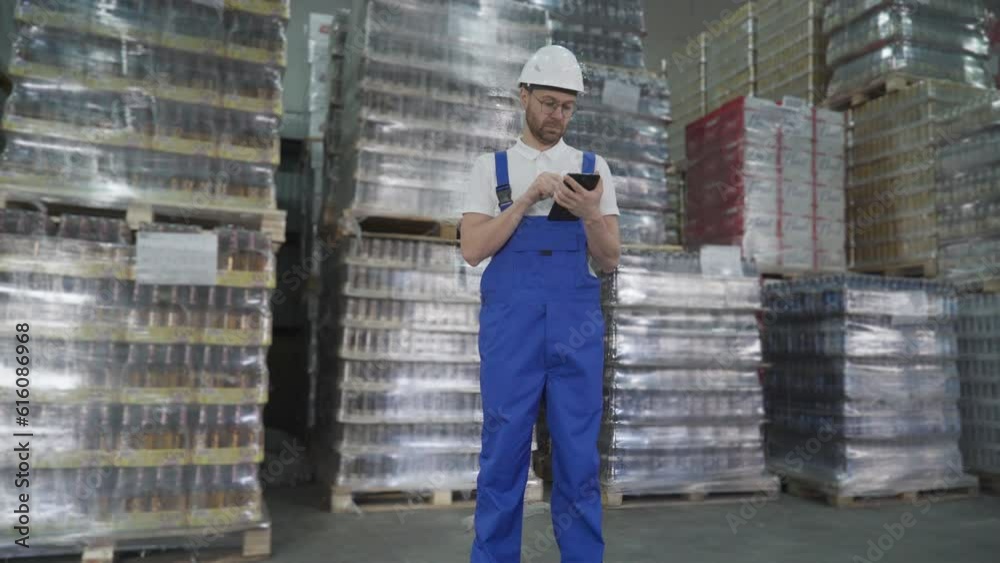Inventory management worker uses a calculator to count the supply. Worker managing the products in the inventory at the facility. Management worker observing the huge storehouse inventory. Inventory management worker uses a calculator to count the supply. Worker managing the products in the inventory at the facility. Management worker observing the huge storehouse inventory.