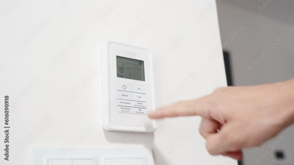 The man sets the lowest temperature on the air conditioning remote control. The man sets the lowest temperature on the air conditioning remote control.