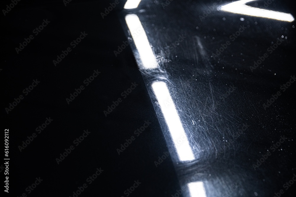 Before and after effect of a paint correction on the paintwork of a black car in a car detailing studio. Paint correction is one of the most important elements of the car detailing process.