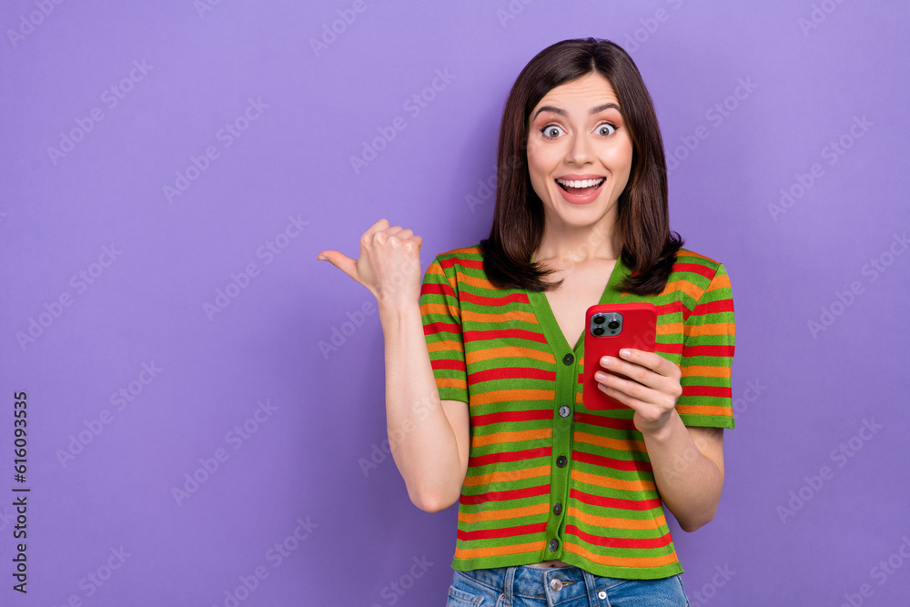Portrait of impressed girl hold smartphone indicating empty space facebook instagram twitter whatsapp isolated on violet background Portrait of impressed girl hold smartphone indicating empty space facebook instagram twitter whatsapp isolated on violet background