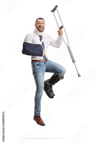 Foto Happy man recovering from an injury and jumping with a crutch