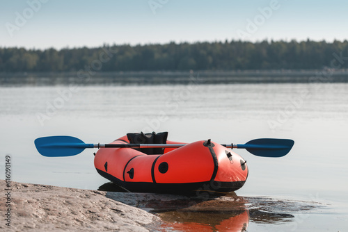 Red packraft with a paddle on the seashore. photo