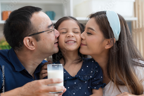 Happy Asian father and mother kissing on daughter cheek in kitchen at home. Happy Asian family spending time together in kitchen at home