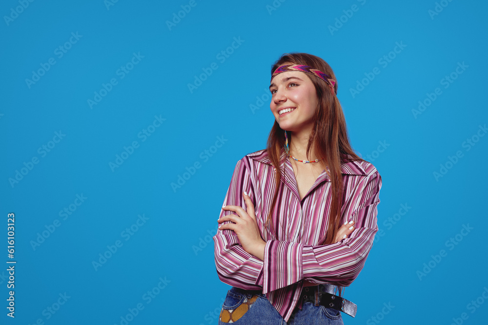 Excited hippie lady wearing pink striped shirt holding hands crossed while looking away at free empty space for text, isolated over blue background. Excited hippie lady wearing pink striped shirt holding hands crossed while looking away at free empty space for text, isolated over blue background.